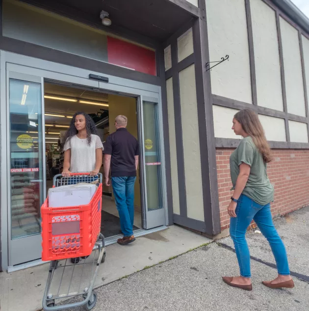 Shoppers walking in and out of a storefront.